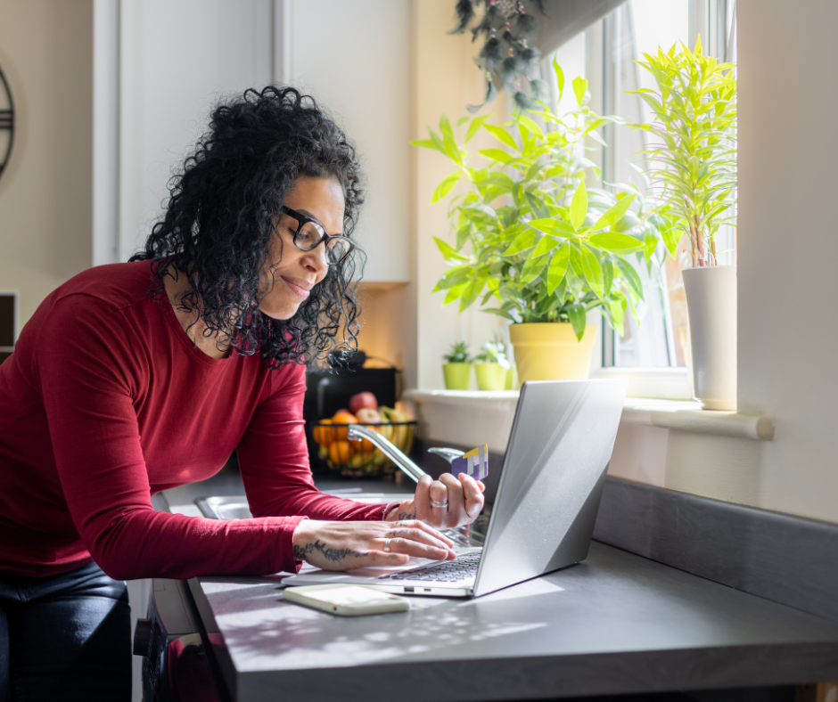 woman with glasses and red shirt using her credit card to pay bills online 