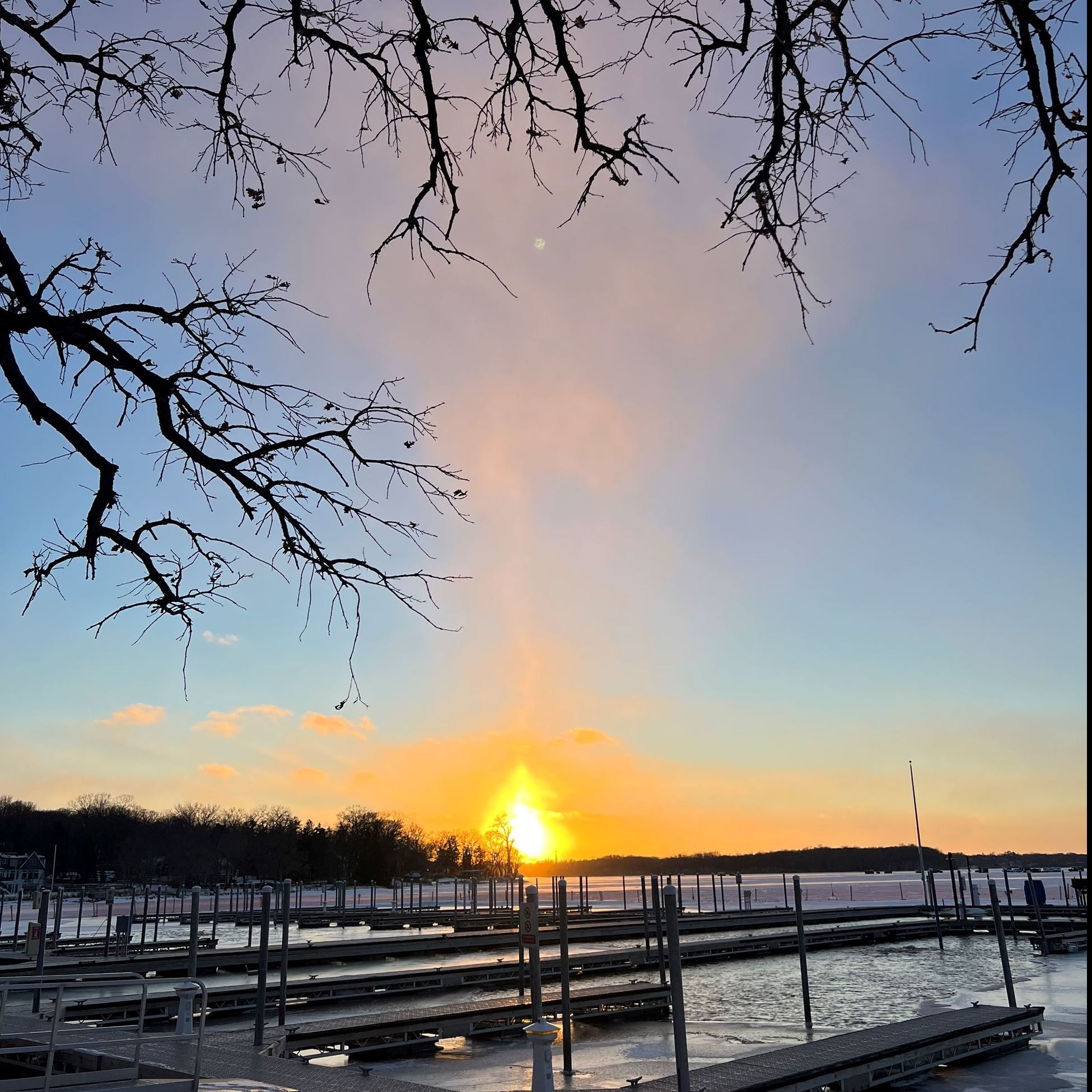rays of sunlight peeking through clouds over docks on a lake